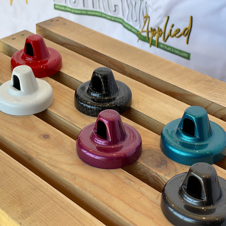 A selection of painted antenna caps for Jeep vehicles, displayed in various colors on a wooden surface by Distinction Applied.