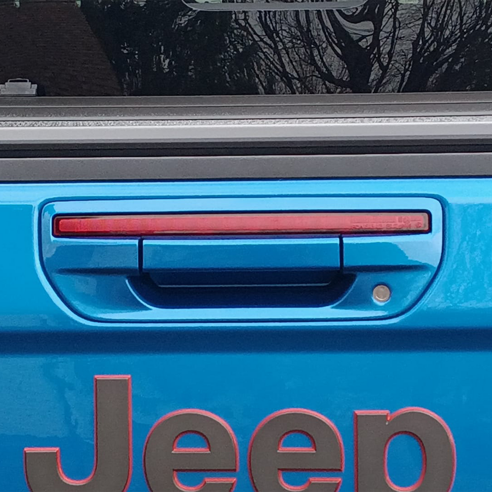 Close-up of a hydro blue Jeep Gladiator with a color-matched tailgate handle and 'Jeep' branding.