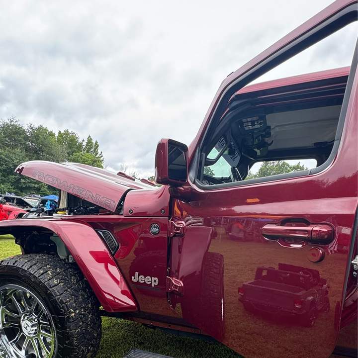 Snazzberry Pearl Jeep Gladiator with open door on a grassy area, highlighting prefinished color-matched door handles