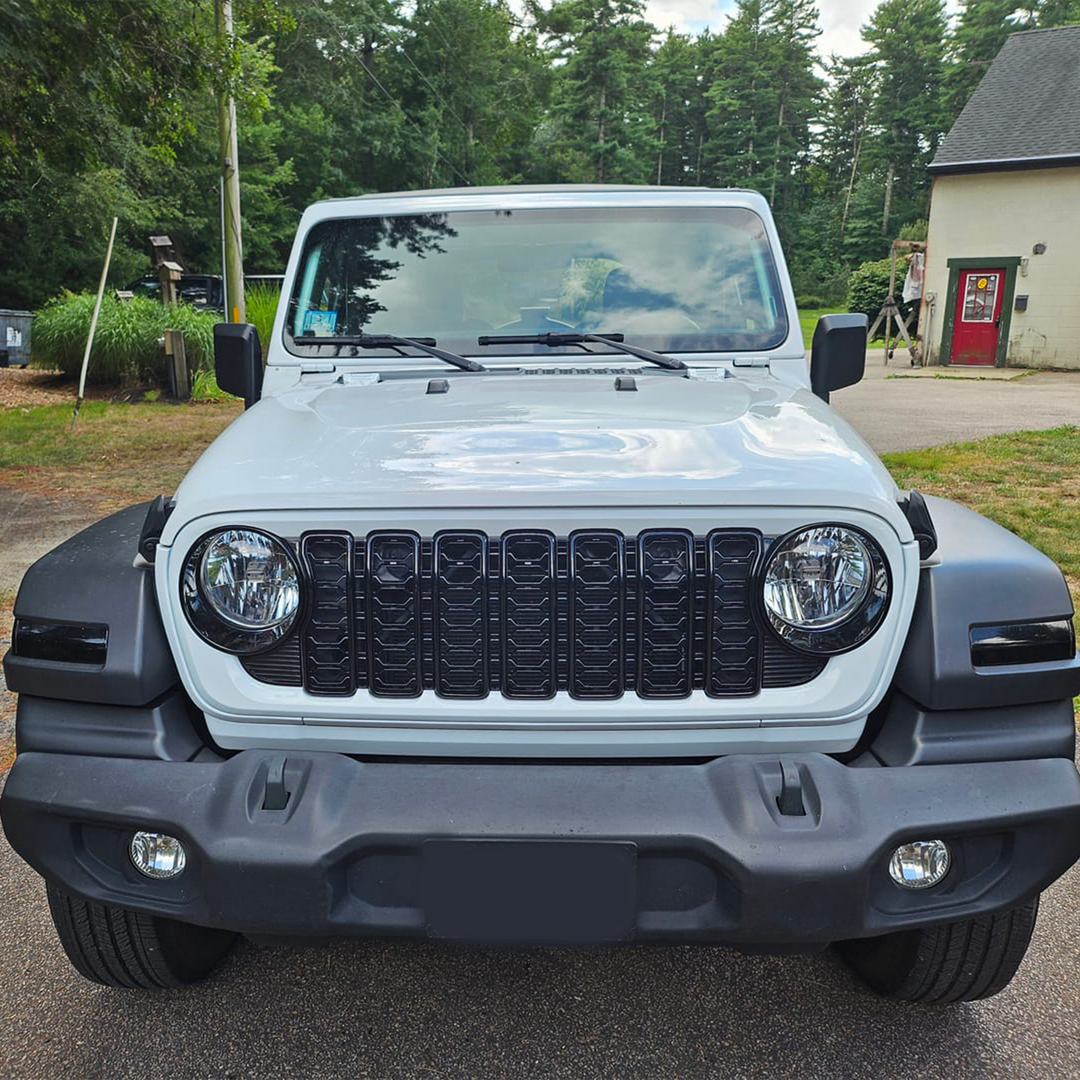 Front view of a Jeep parked on street with  with trees and a building in the background.24 Aftermarket bright white grille and surround and black trim and mesh