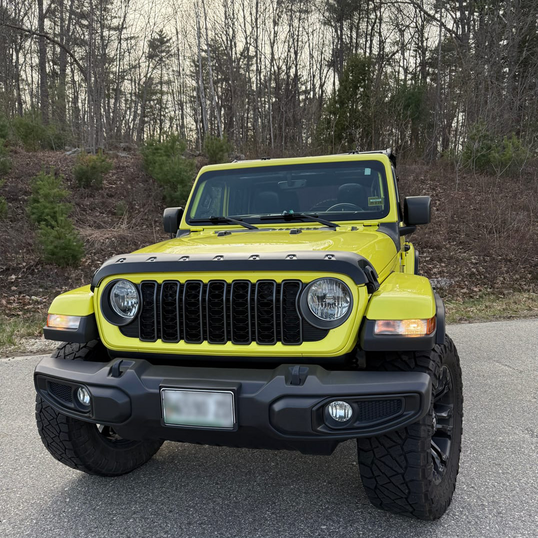 Jeep Wrangler '24 Aftermarket Grille and surround in High Velocity Yellow on a road with trees in the background