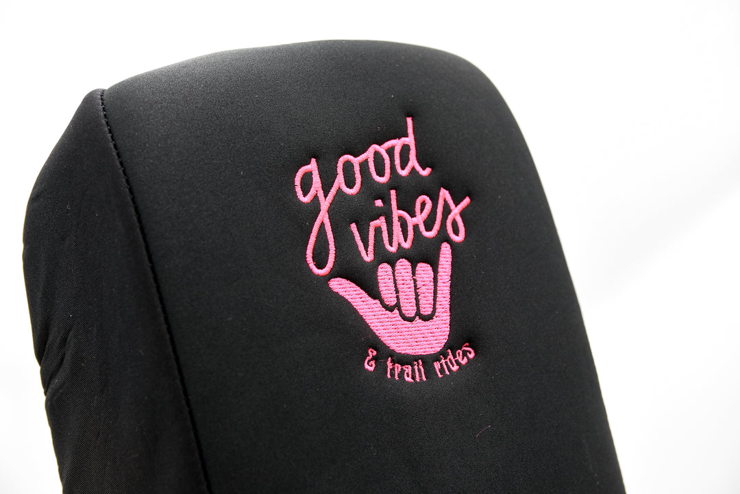 Black console cover with pink 'good vibes & trail rides' text and surfer hand symbol on a white background closeup